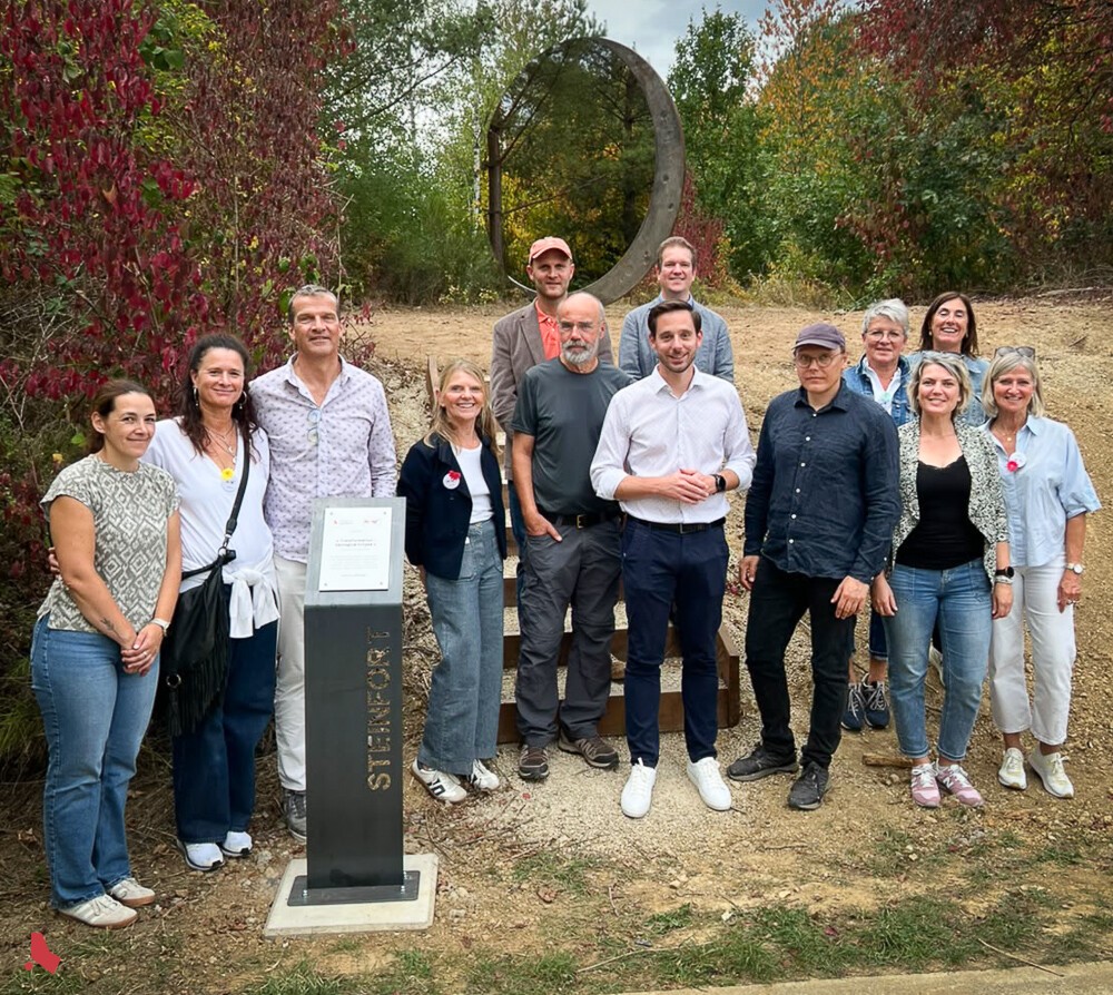 Photo de groupe autour de la stèle de la sculpture « Transformation », avec l'œuvre en arrière-plan