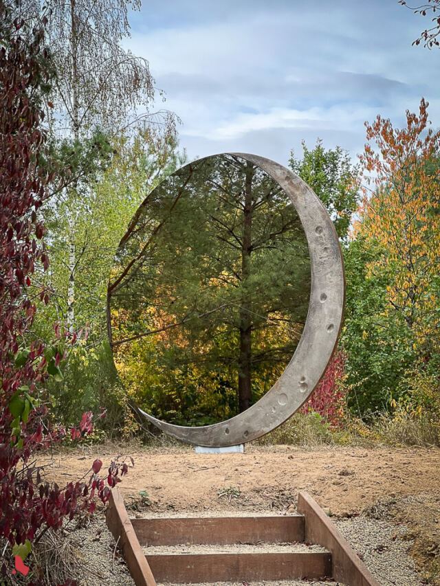 La sculpture « Transformation » de Markus Hoffmann, un disque en miroir et en métal qui reflète la forêt, au Mirador « Op der Berk »