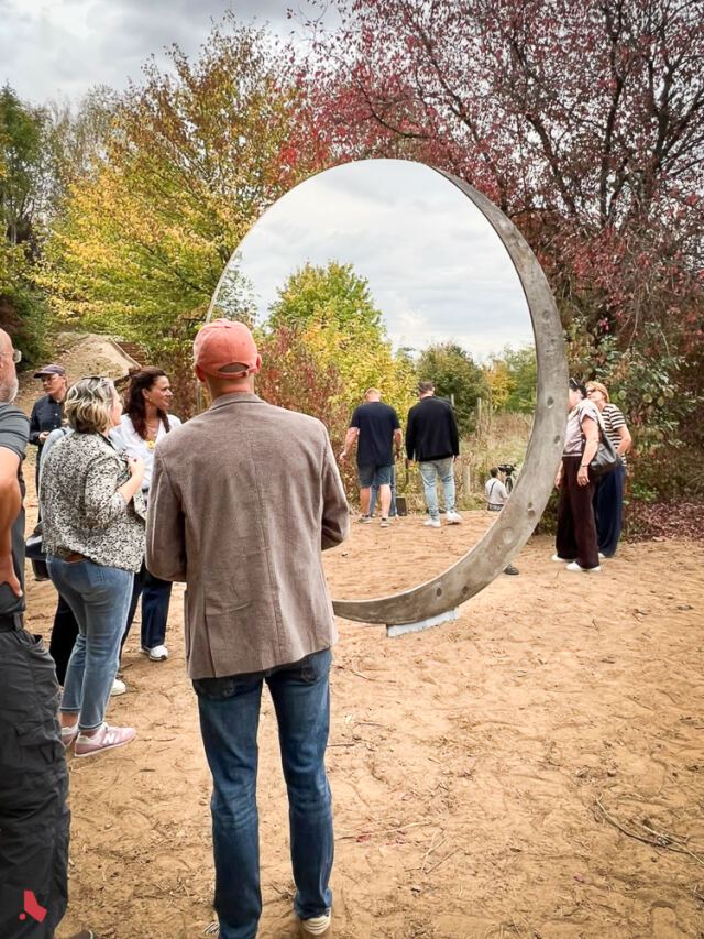 Des invité·e·s découvrent la sculpture « Transformation », un grand disque en miroir et en métal, lors de son inauguration au Mirador « Op der Berk »
