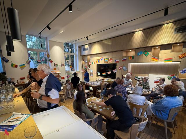 Salle du Bierger*Haus animée pendant l'Afterwork interculturel, avec des participant·e·s de tous âges autour des tables
