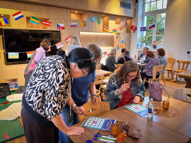 Des participantes remplissent des grilles de jeu sur une table décorée de feuilles d'automne, à l'Afterwork interculturel