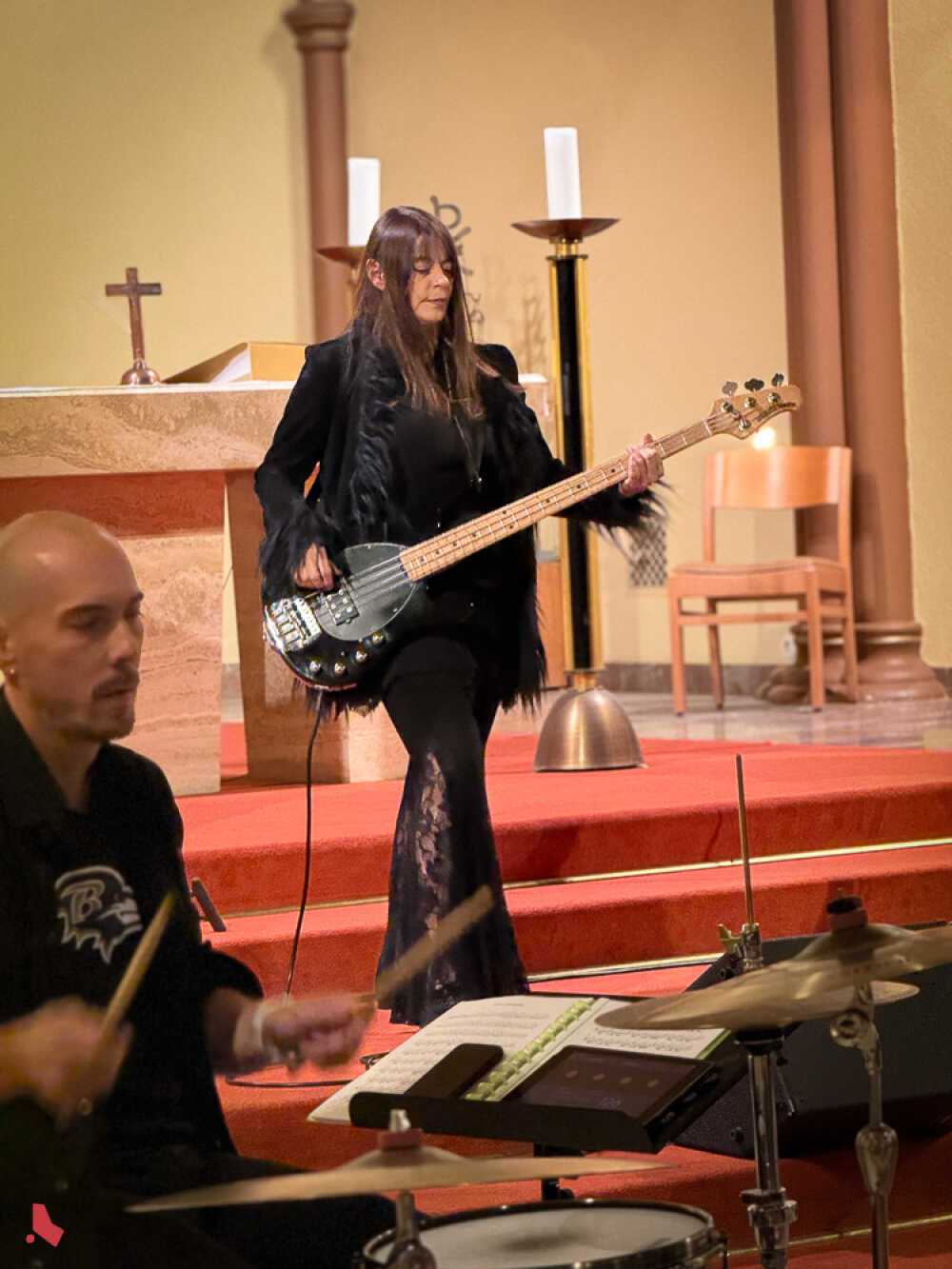 La bassiste du groupe ShadoWhisperS joue sur les marches de l’autel, devant le batteur, lors du concert « Metal & Pipes »