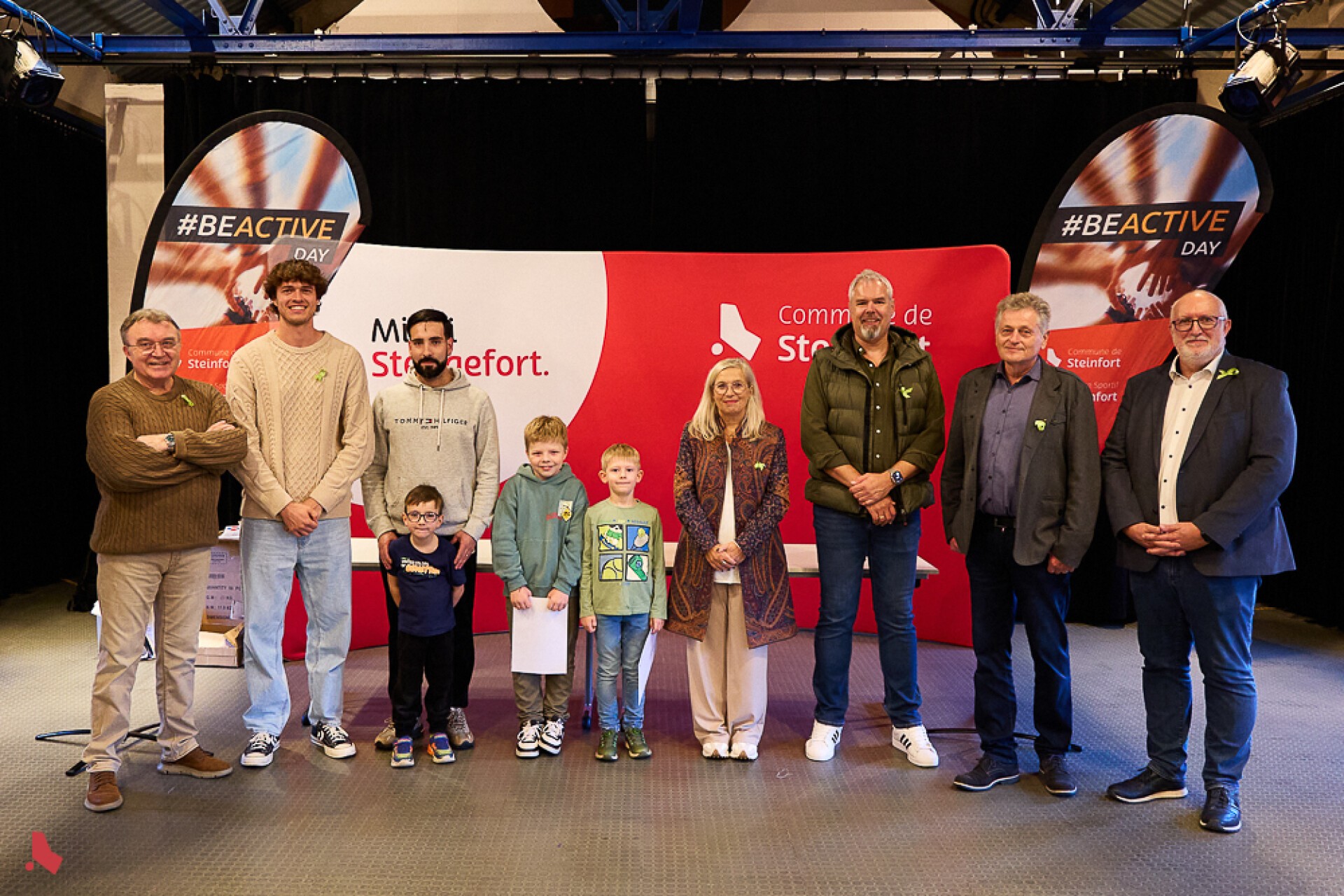 Photo de groupe des gagnant·e·s du quiz du #BeActiveDay, dont trois enfants, devant le kakémono de la Commune de Steinfort