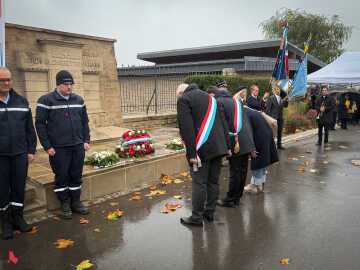Des élu·e·s s’inclinent devant le monument aux morts, où sont déposées les gerbes et les pierres du souvenir