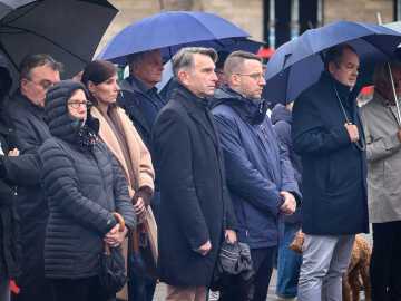 Des participant·e·s se recueillent sous des parapluies lors de la Journée de commémoration nationale