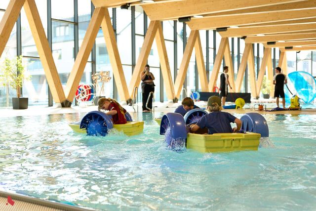 Des enfants dans des bateaux à roues à aubes, dans le bassin de la piscine communale, lors du Be Active Day