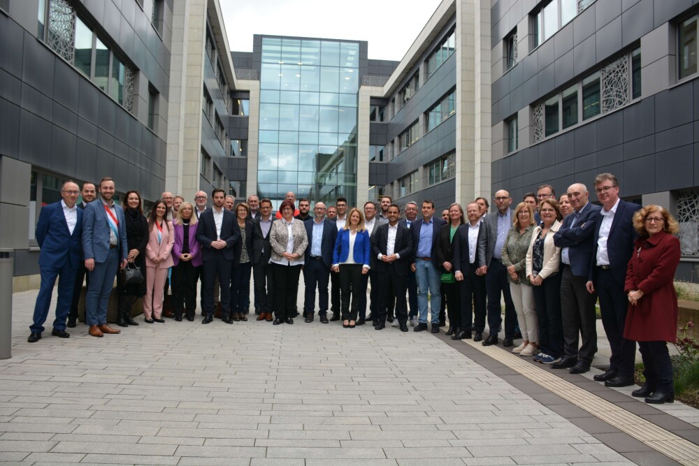 Photo de groupe d'une quarantaine de personnes dans une cour, devant des bâtiments de bureaux, dans le cadre du Gemengepakt