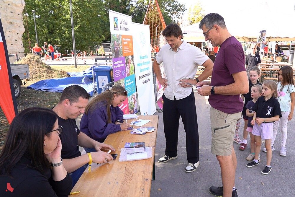 Stand au Be Active Day : des visiteur·euse·s, dont des enfants, attendent devant une table où trois personnes sont assises pour donner des dédicaces